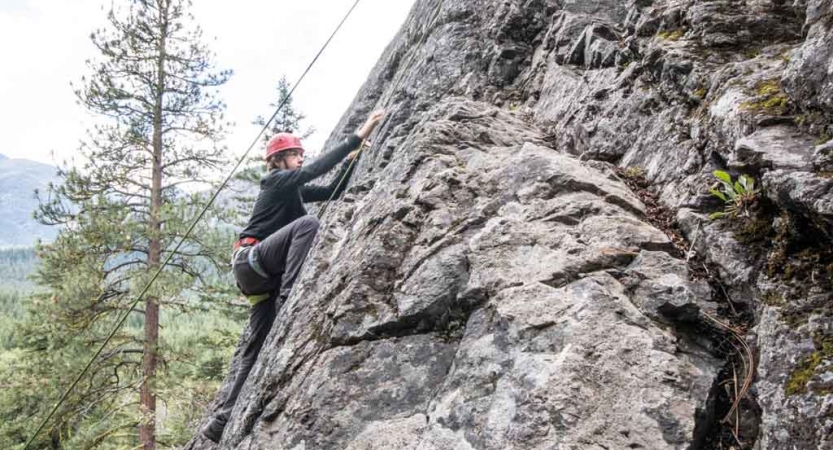 a student ascends a rock wall on a rock climbing expedition with outward bound